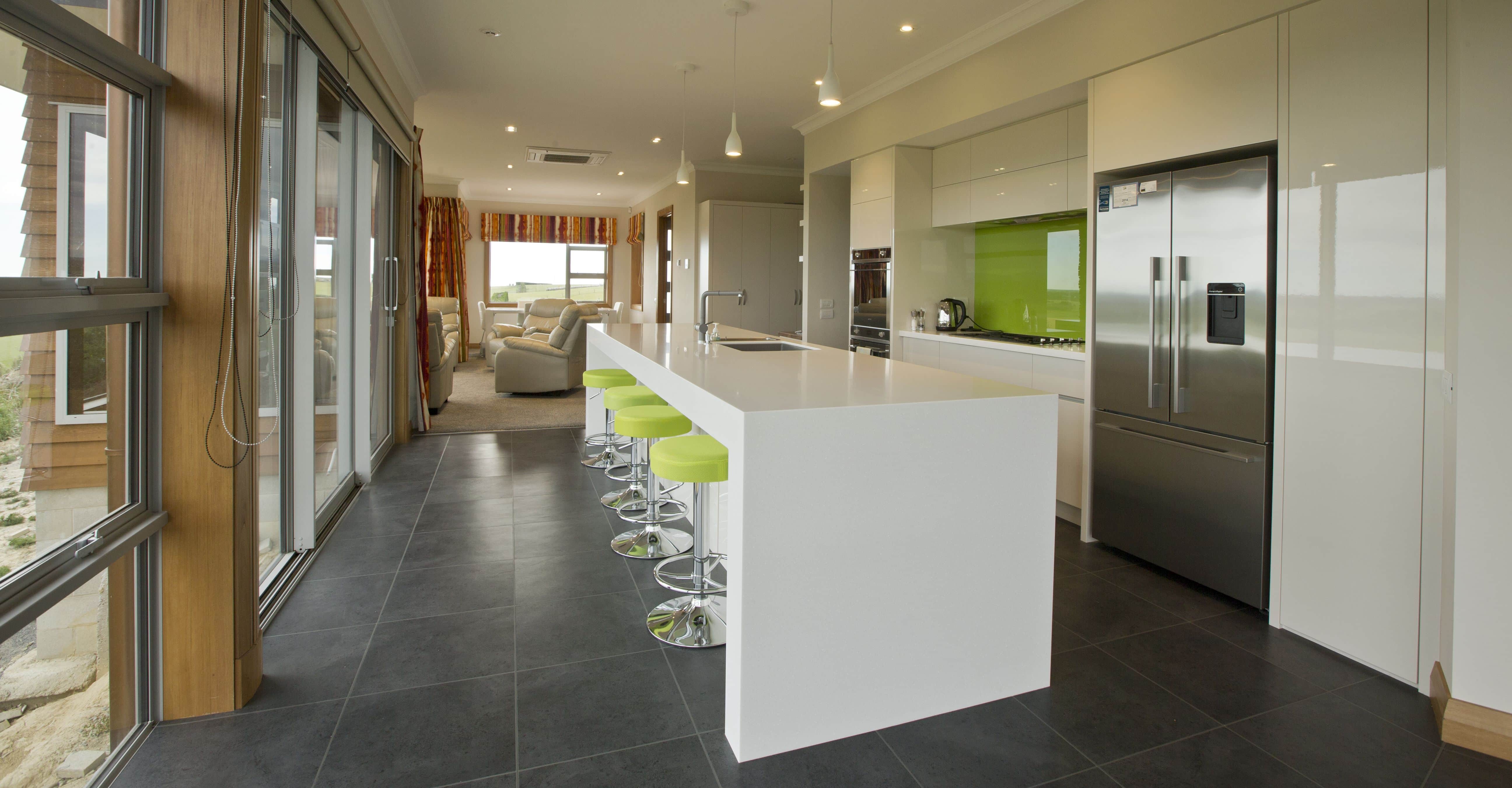  A lime green splash back matching the bar stools increases the pop of colour from the living room