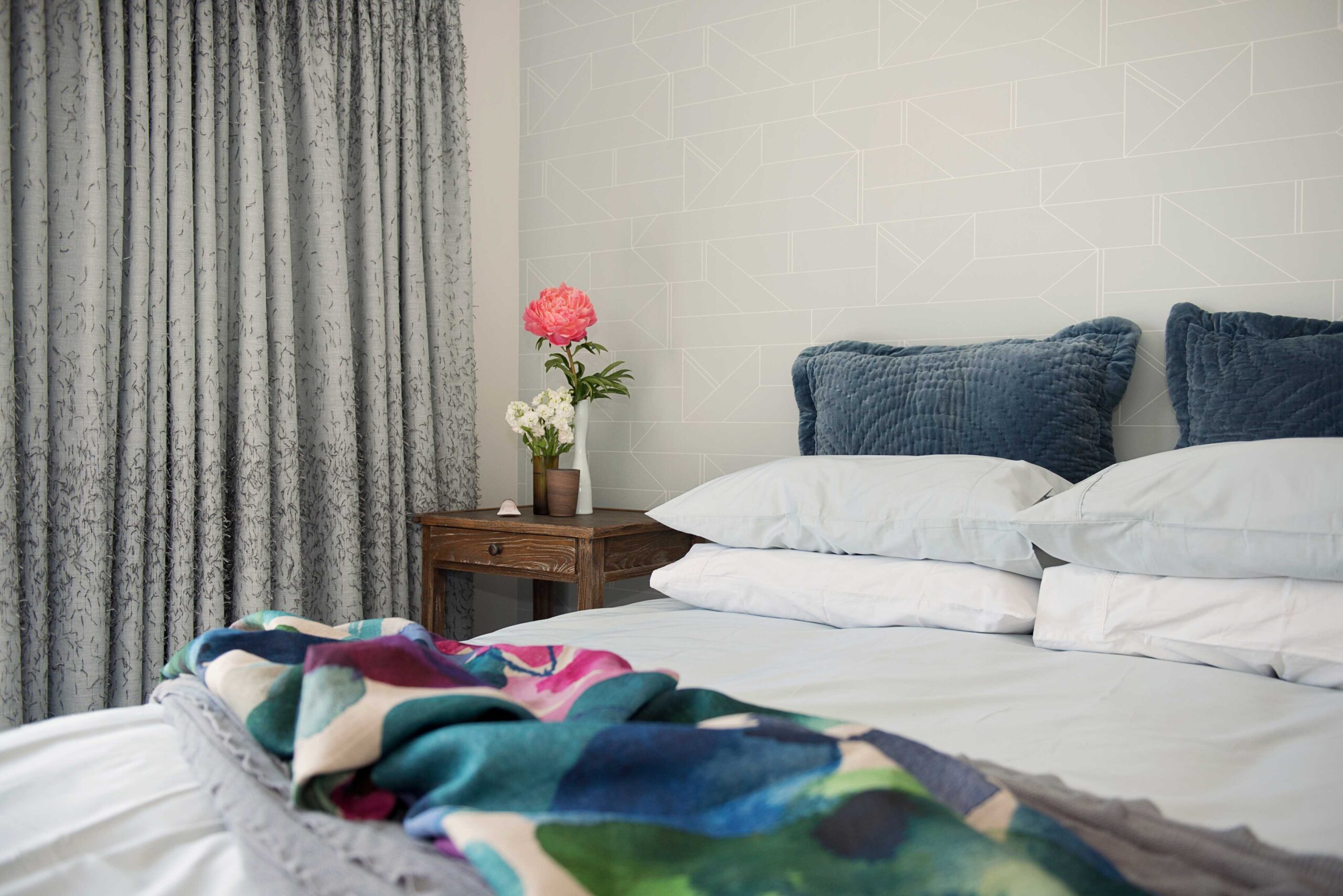  Main bedroom with colourful throws and feature wallpaper.